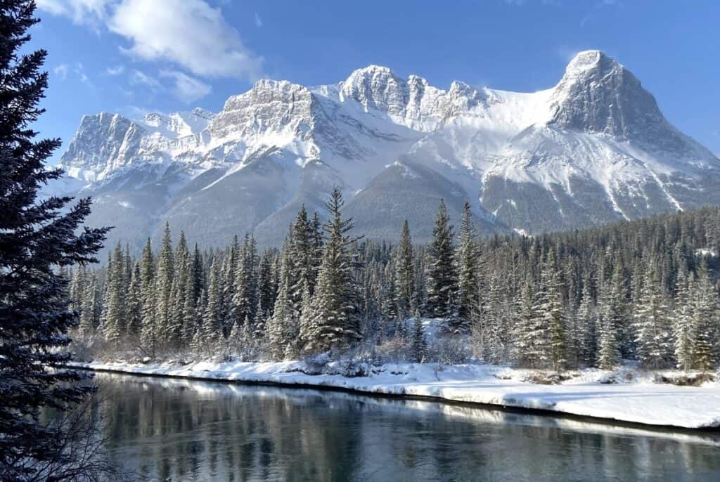 A snowy ha ling peak and snow covered trees from canmore engine bridge in winter