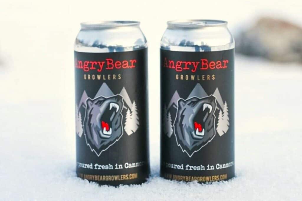 Two cans of angry bear growlers beer sit in the snow one of the popular breweries in canmore alberta