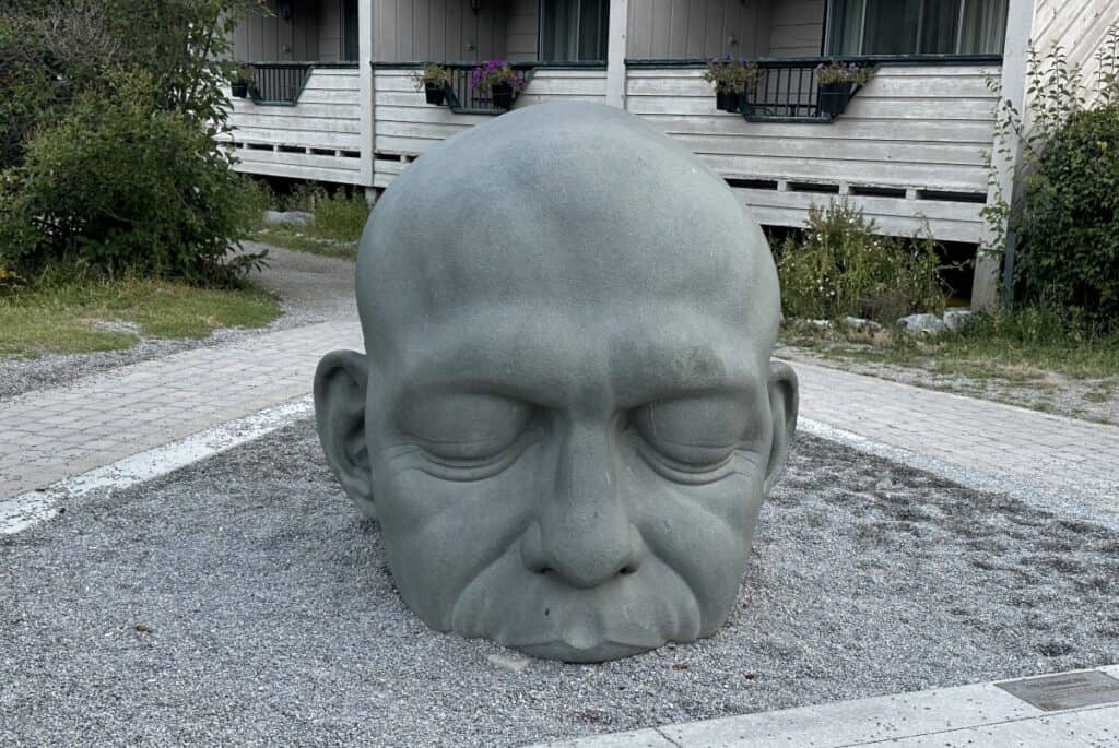 A front view of the sculpture known as canmore big head which depicts a large head rising from the ground