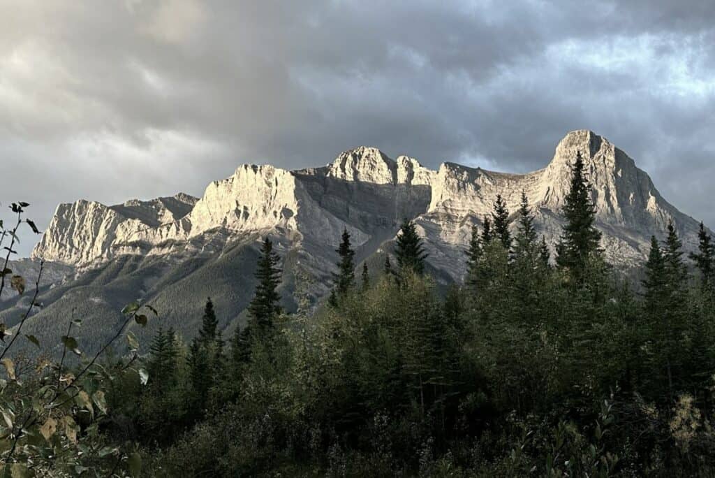 Dramatic ha ling peak with dark moody clouds in early morning light near the bow river loop trail canmore alberta
