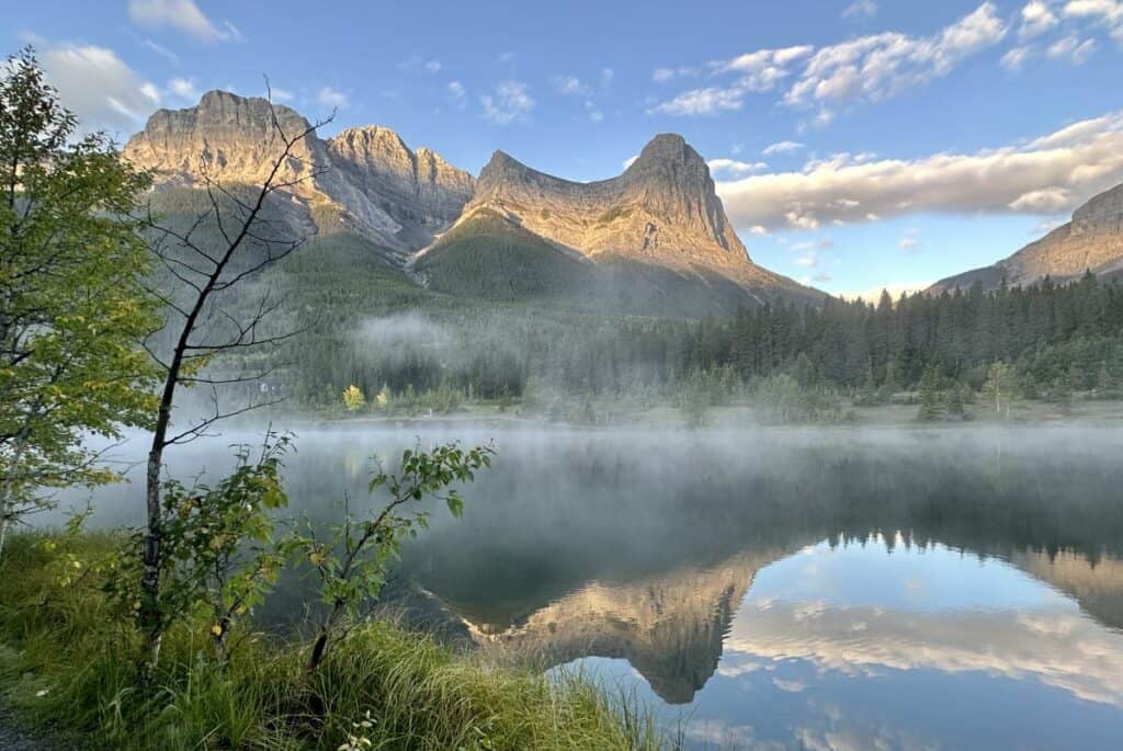 A serene quarry lake at sunrise with mountain backdrop one of the best free things to do in canmore