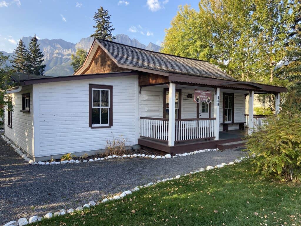 A small white log house is the historic north west mounted police barracks is one of best free things to do in canmore