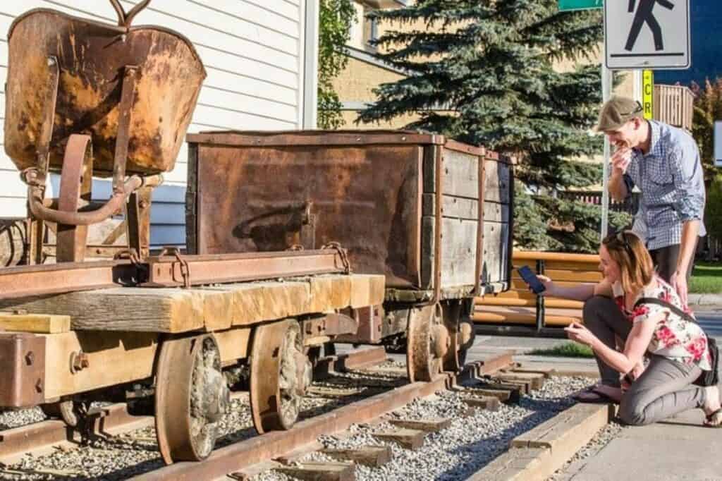 Two people examine an old rail truck for a smugglers blue clue solving adventure one of the unique things to do in canmore