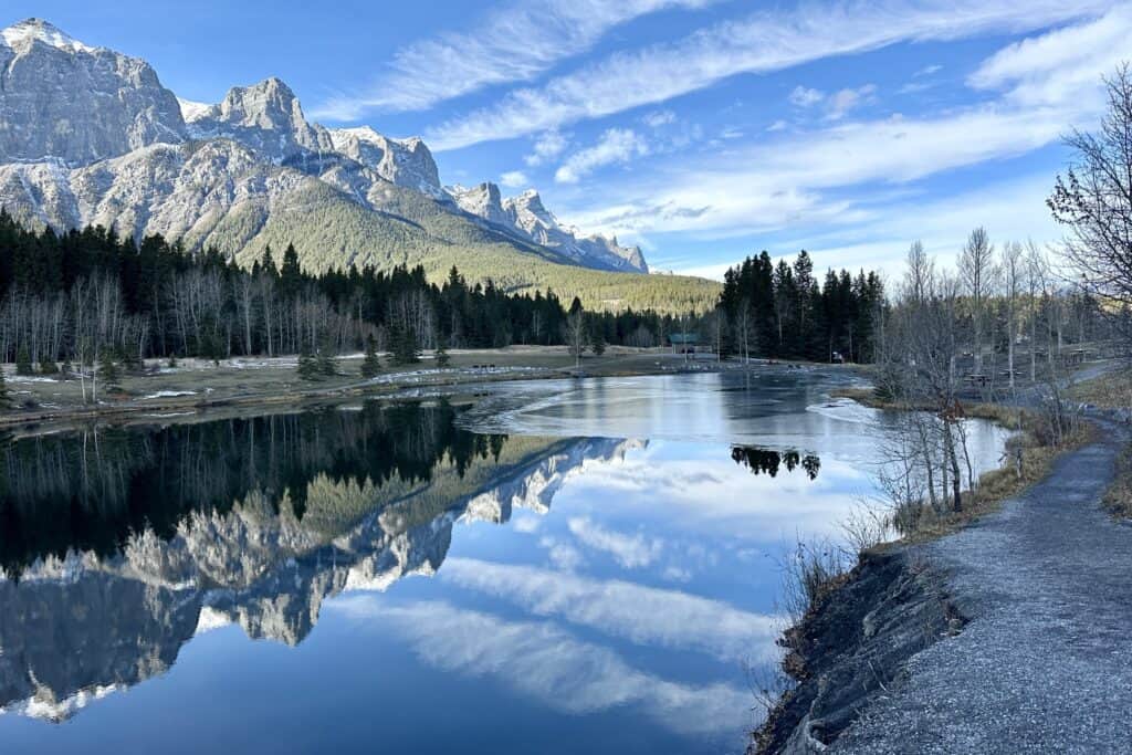 Early winter on quarry lake loop canmore with east end rundle reflected in the lake below a blue sky