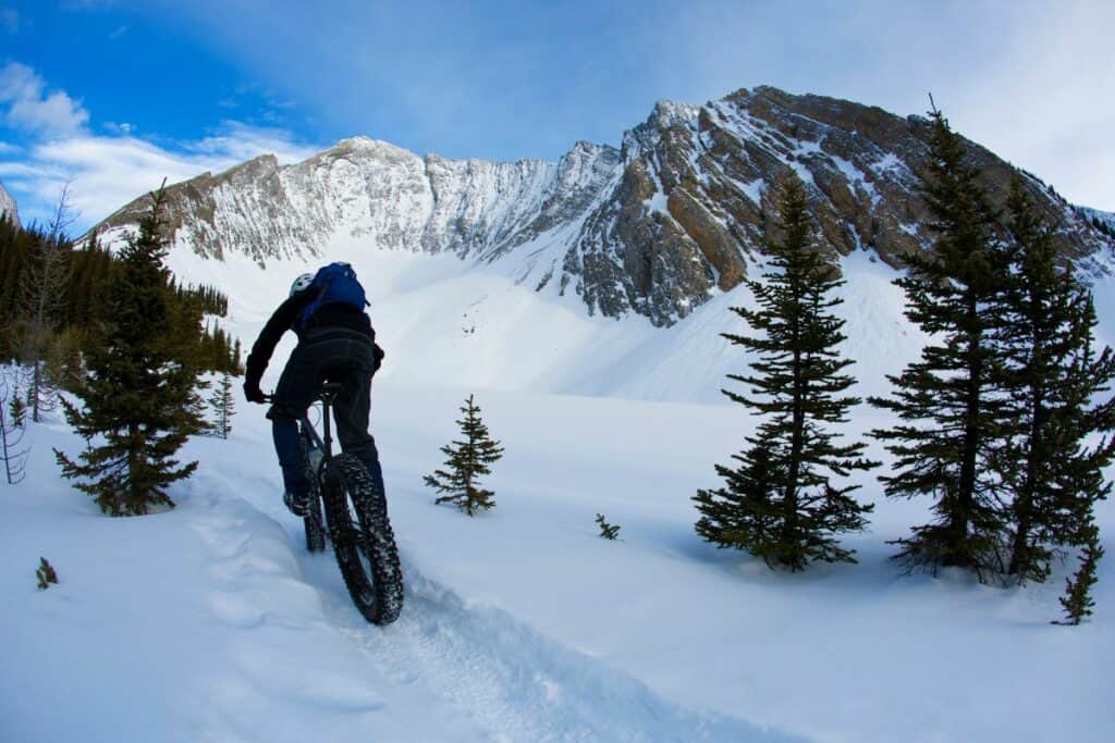 A man rides a fat bike through snowy mountains one of the unique things to do in canmore