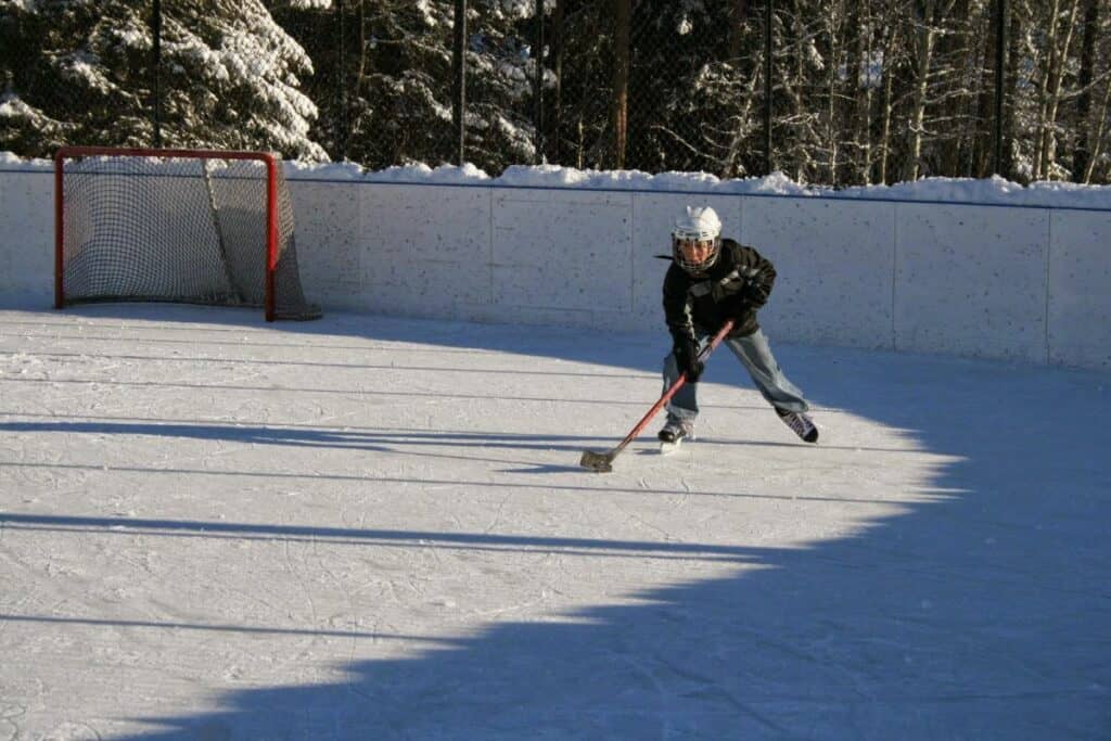 A young boy plays ice hockey on larch ice rink one of the best free things to do in canmore