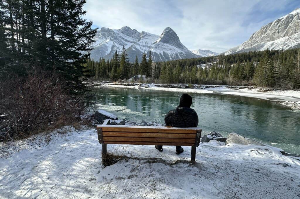 A peaceful bench beside canmore engine bridge in winter with ha ling peak in background
