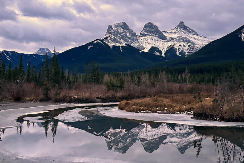 The three sisters peaks reflected in a pond taken from three sisters viewpoint one of the best free things to do in canmore